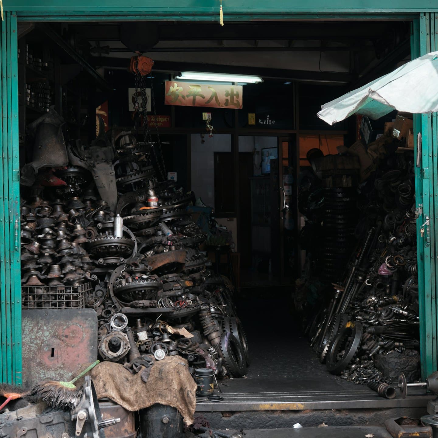 Interno disordinato di un negozio di ricambi auto con cumuli di componenti del motore.